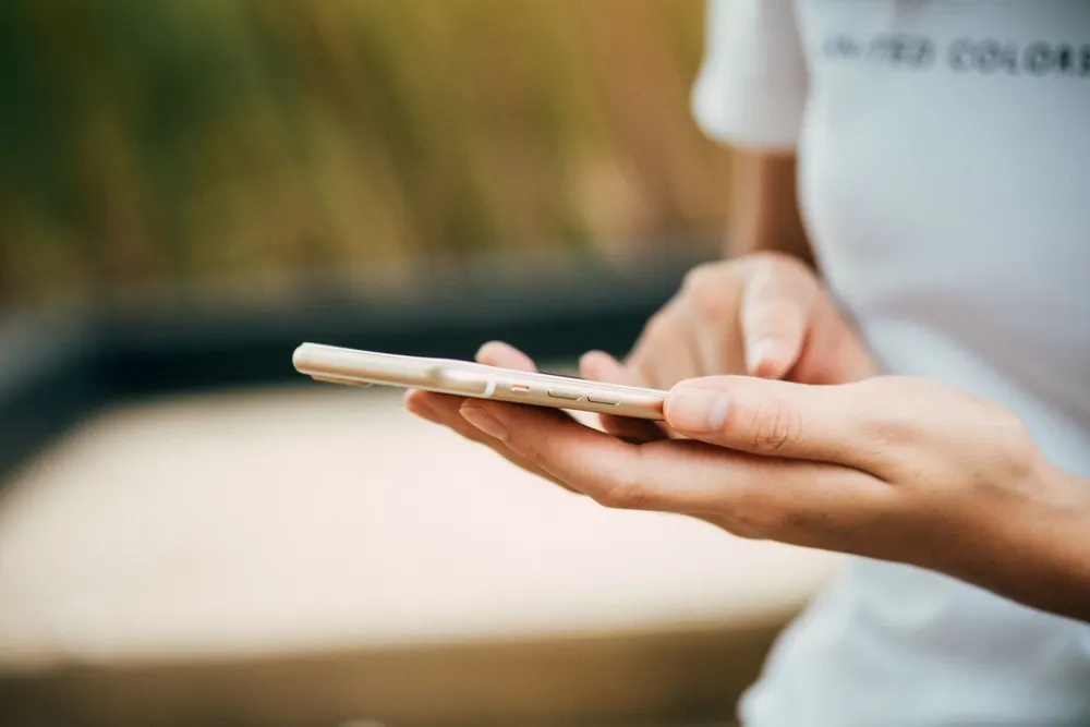 Une personne consulte son téléphone à la lumière du jour.